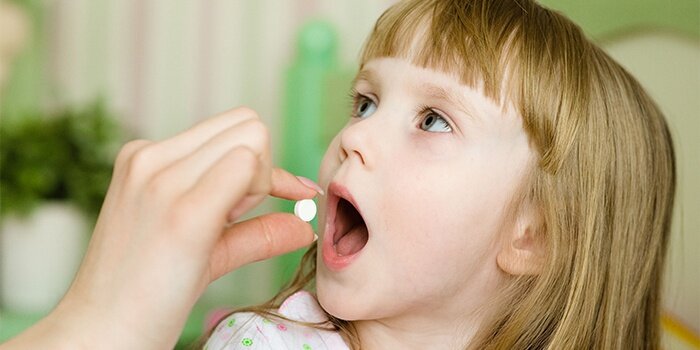На фото: прием таблетки ребенком